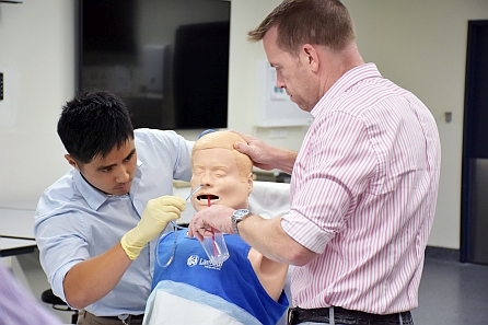 Two men training on an dummy patient doll