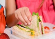 Hand of a child picking sandwich from a lunch box