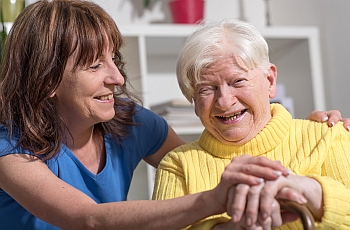 Image of an smiling old woman and her carer